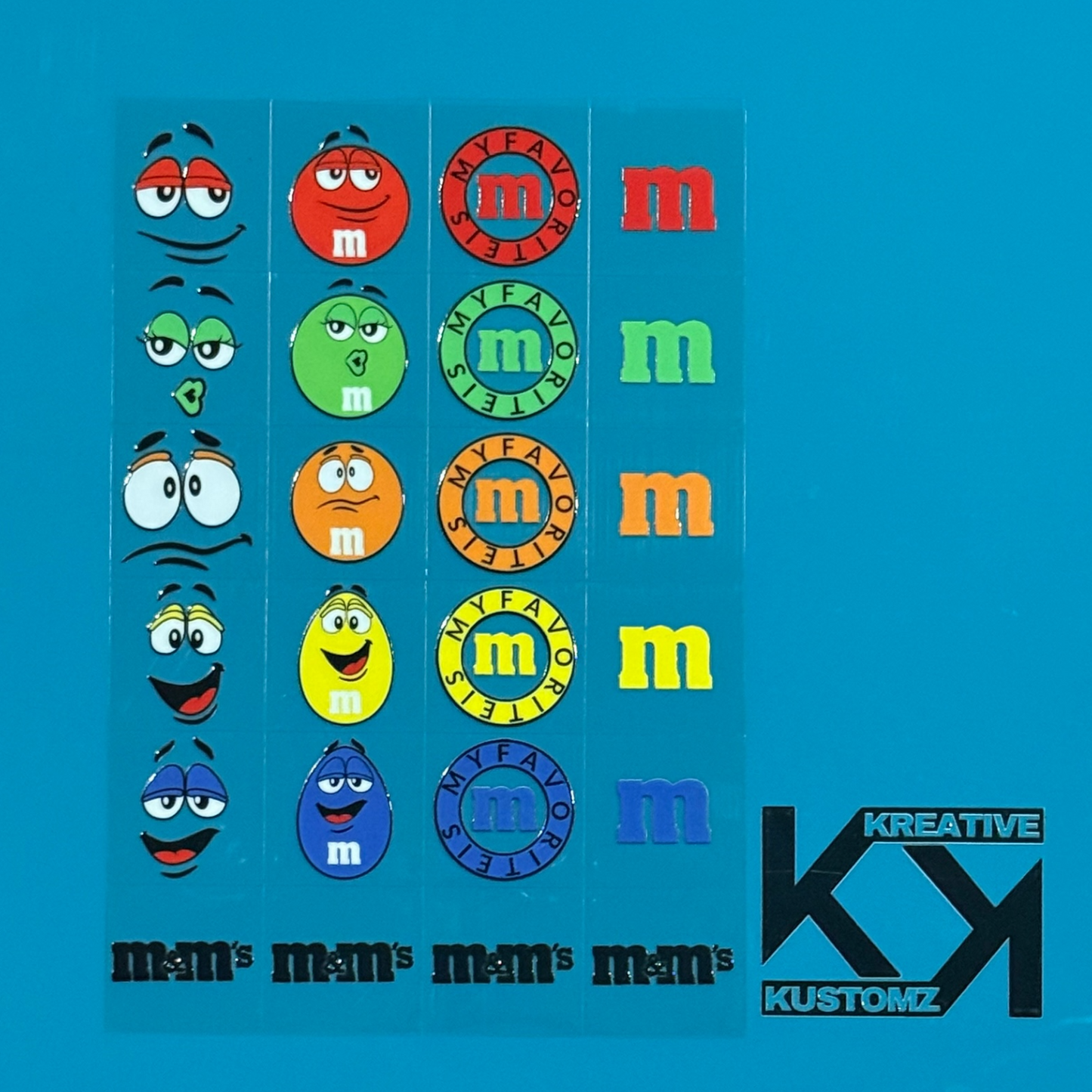 A sheet of M&M themed UV DTF adhesive decals featuring character faces, logos, and text.