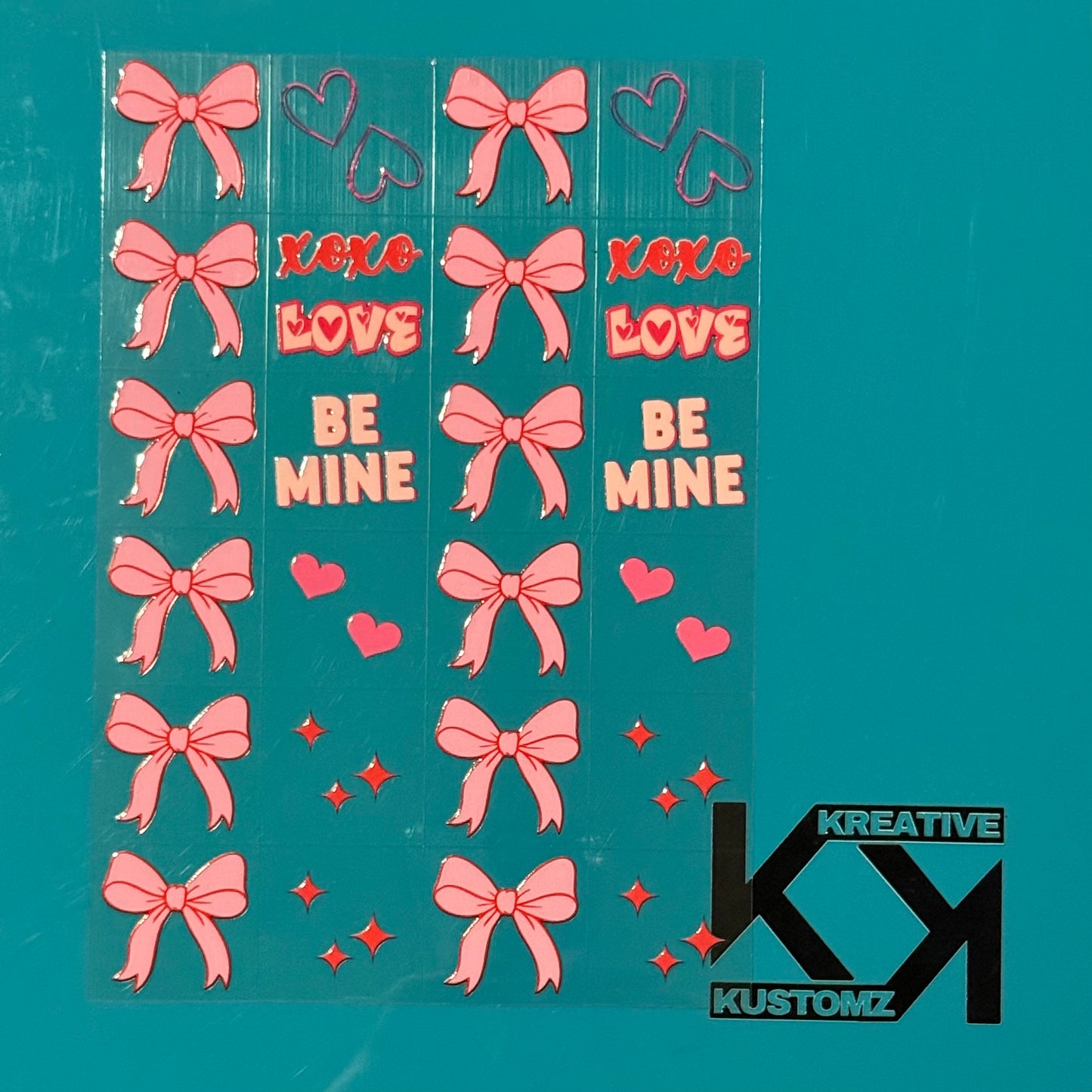 An A5 sheet of pink bow, heart, and Valentine-themed UV DTF decals on a teal background.