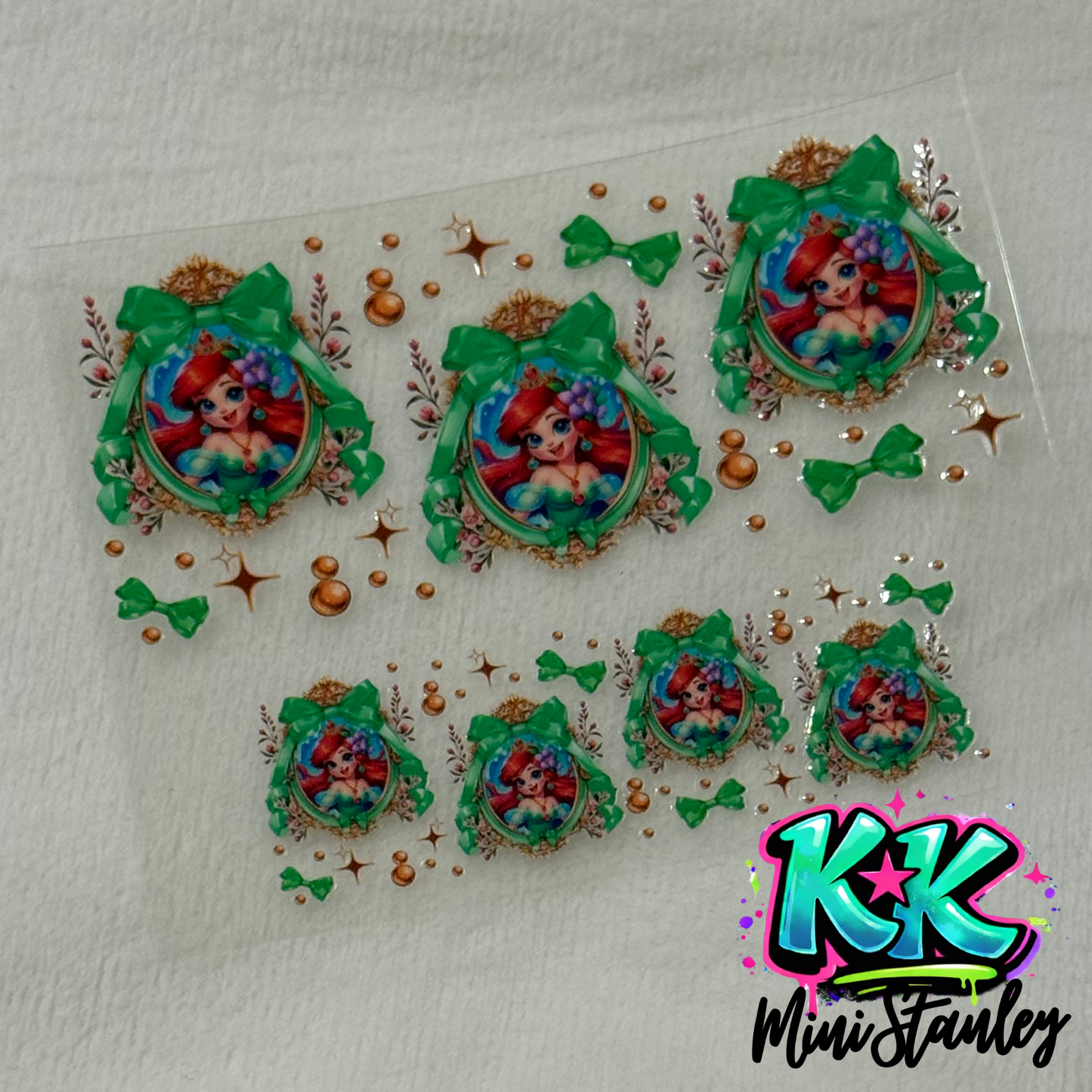 A sheet of UV DTF adhesive wraps featuring Ariel in ornate frames with green bows and bubbles.