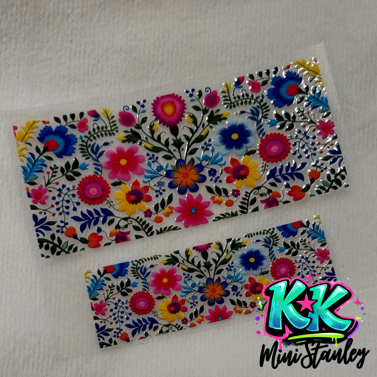 Two rectangular UV DTF adhesive wraps featuring a colorful floral pattern on a clear background.