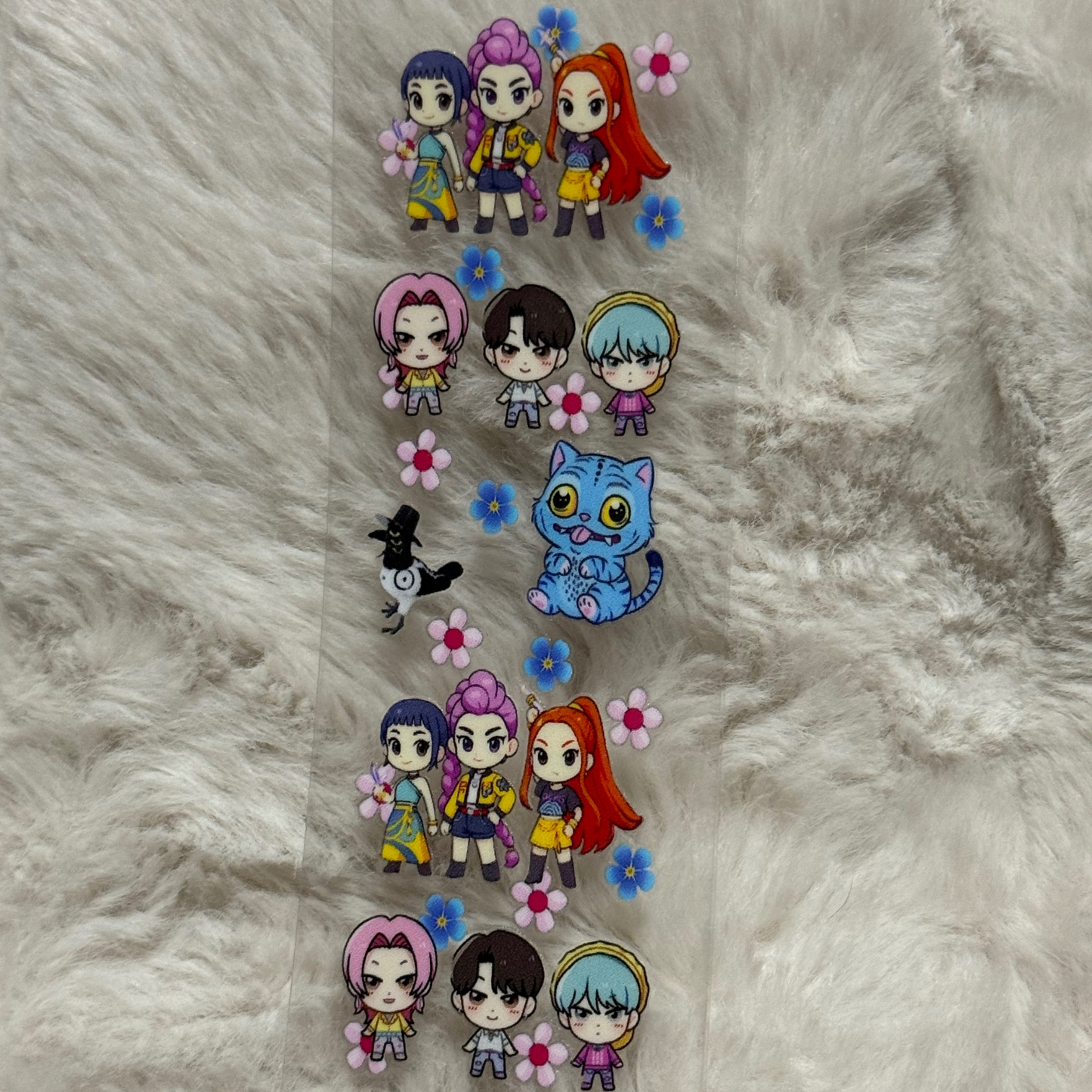 A clear UV DTF adhesive pen wrap featuring repeating chibi character and cat illustrations.