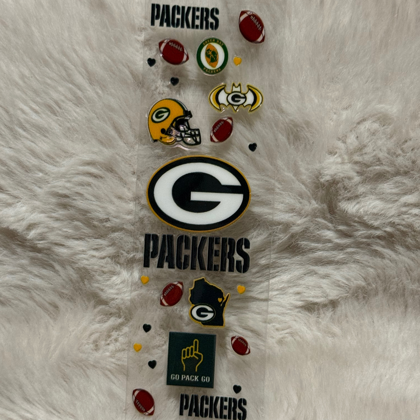 A Green Bay Packers themed UV DTF adhesive pen wrap featuring team logos and football icons.