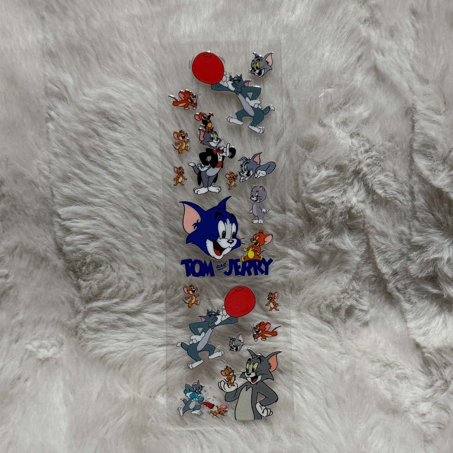 A clear adhesive pen wrap featuring various Tom and Jerry character illustrations.