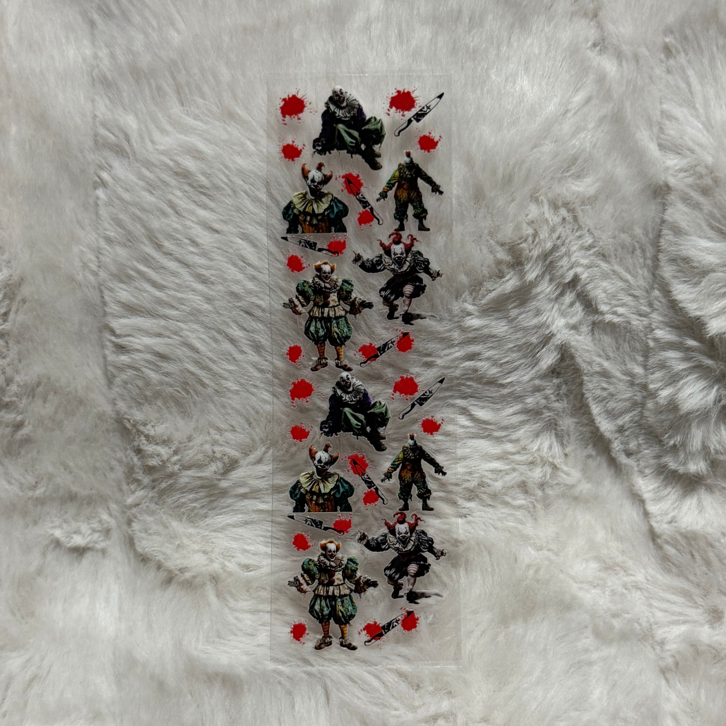 A UV DTF adhesive pen wrap featuring a repeating pattern of scary clowns and bloody knives.