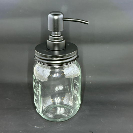A clear glass mason jar soap dispenser with a matte black pump lid.