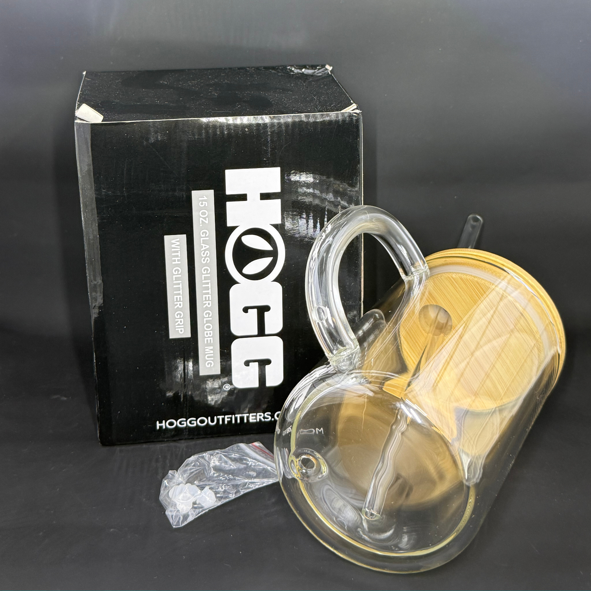 A 15oz double-wall glass mug with a wooden lid, straw, and plug, shown next to its HOGG box.