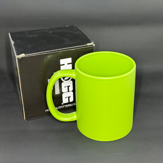 A vibrant green matte ceramic mug sits next to its black branded packaging box.