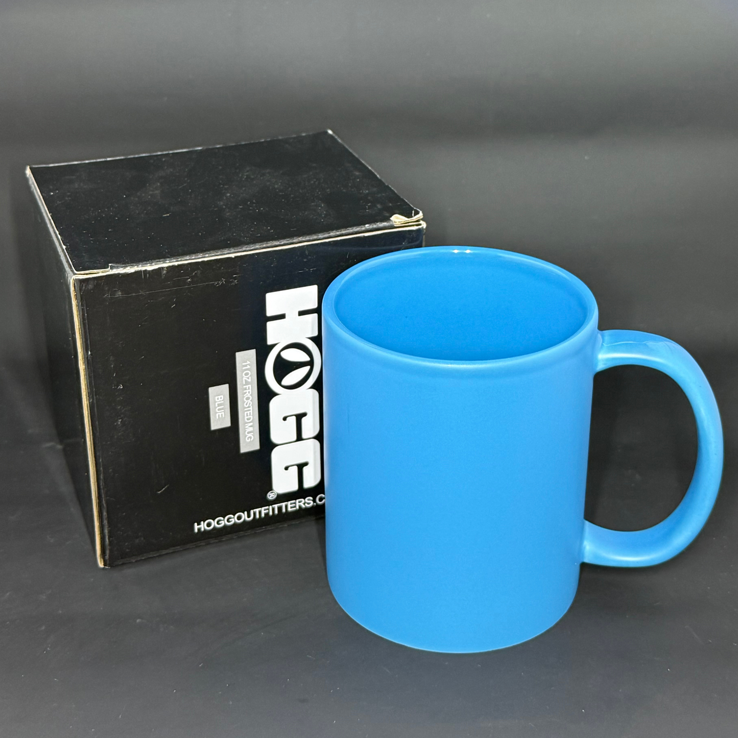 A vibrant blue matte ceramic mug stands next to its black HOGG branded product box.