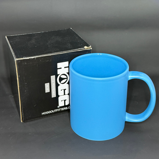 A vibrant blue matte ceramic mug stands next to its black HOGG branded product box.