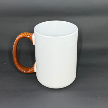 A white ceramic mug with a brown, football-textured handle against a dark background.