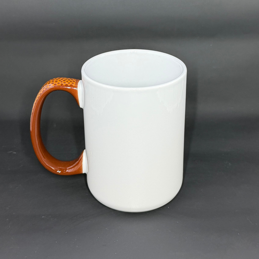 A white ceramic mug with a brown, football-textured handle against a dark background.