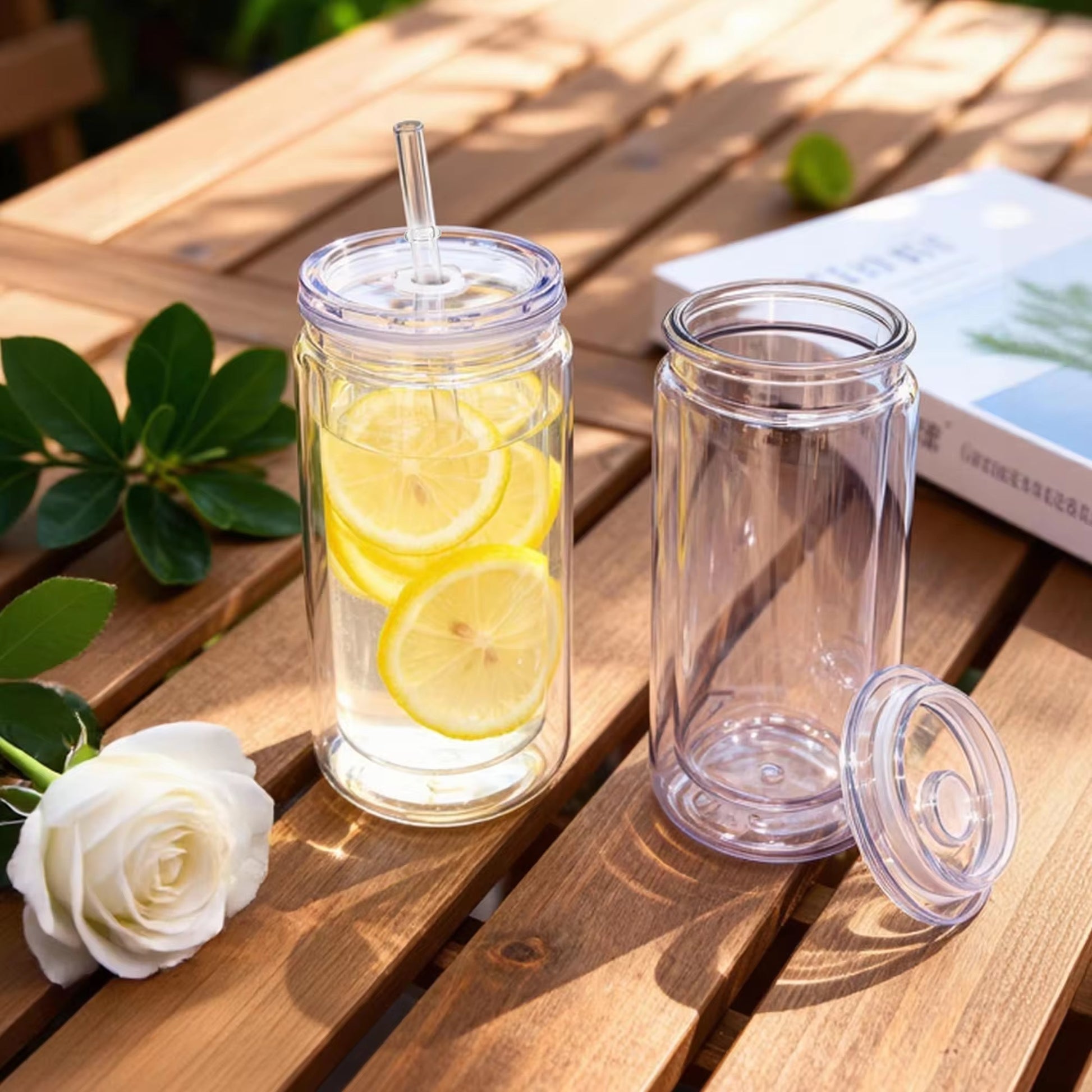 Two clear double-walled acrylic tumblers with lids and a straw, one filled with lemon water.