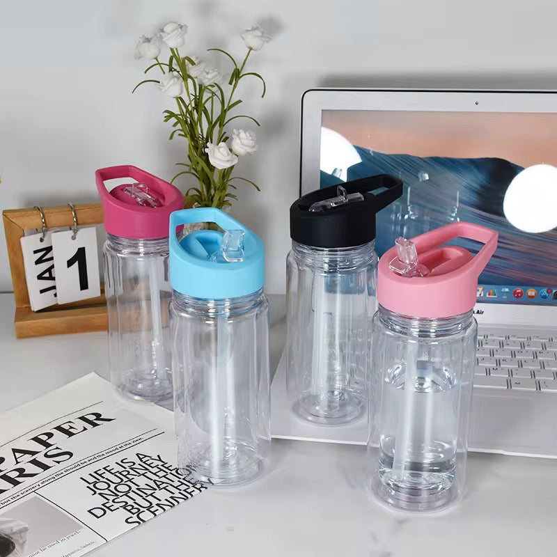 Four clear acrylic tumblers with colorful lids and straws stand on a desk next to a laptop.