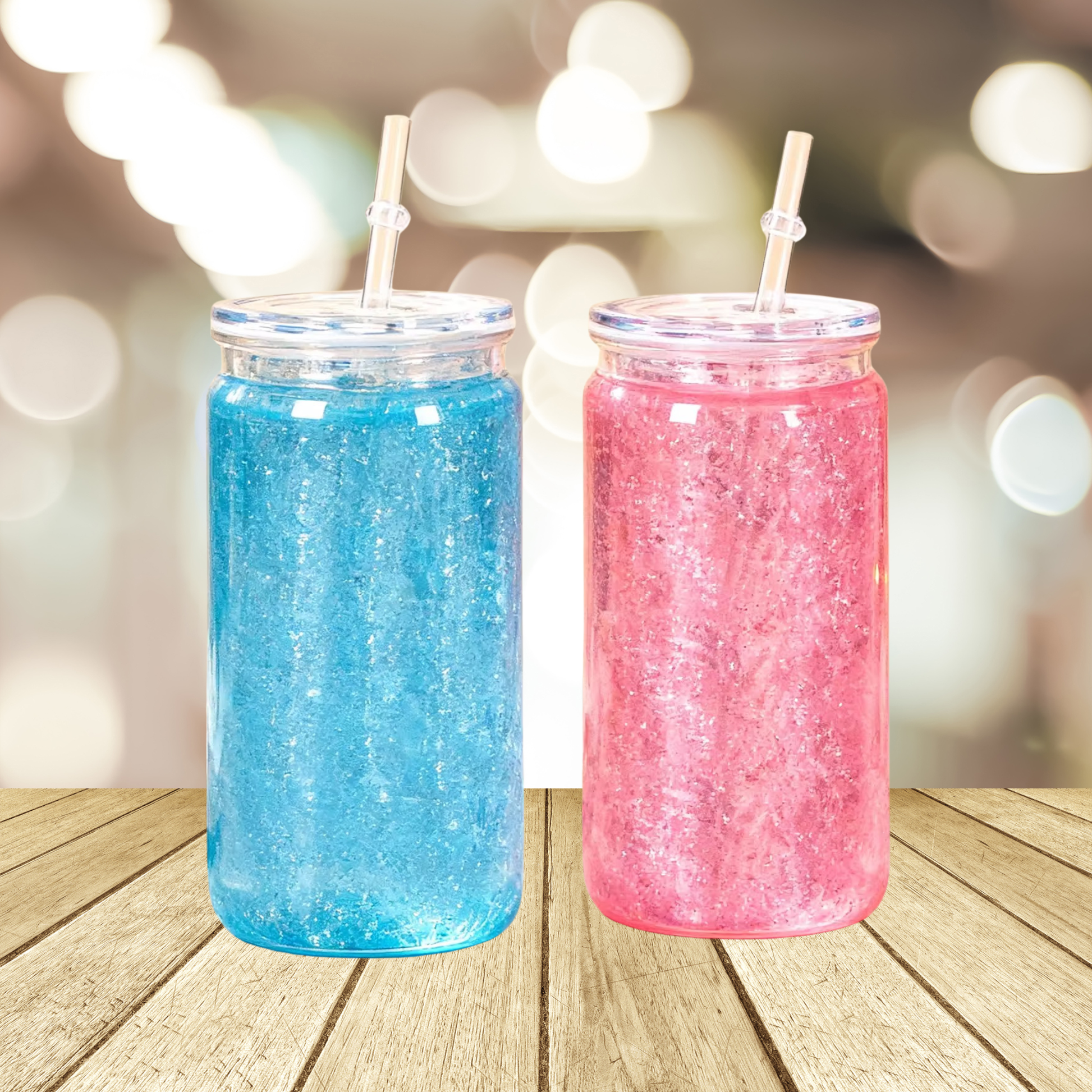 Two 16oz acrylic snow globe tumblers with lids and straws, one filled with blue and one with pink glitter.