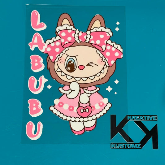 A pink Labubu girl character sticker with a polka dot bow and dress on a clear backing.