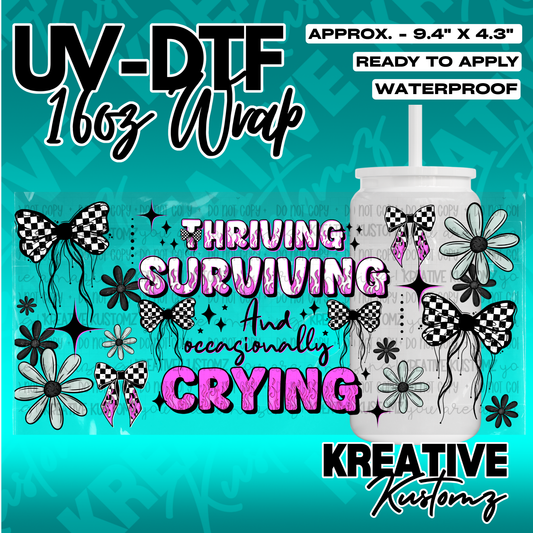 A UV DTF cup wrap featuring checkered bows, flowers, and the text Thriving Surviving and Crying.