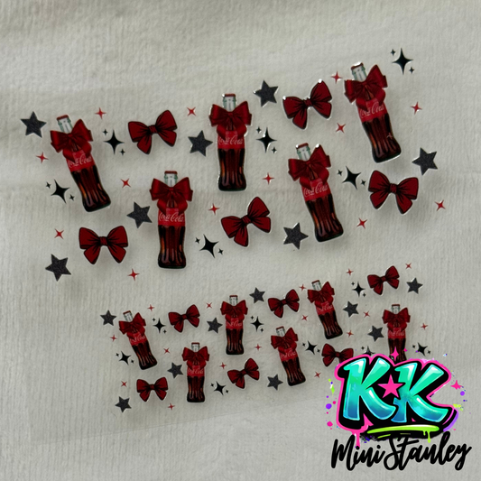 A sheet of UV DTF adhesive decals featuring Coca-Cola bottles, red bows, and black stars.