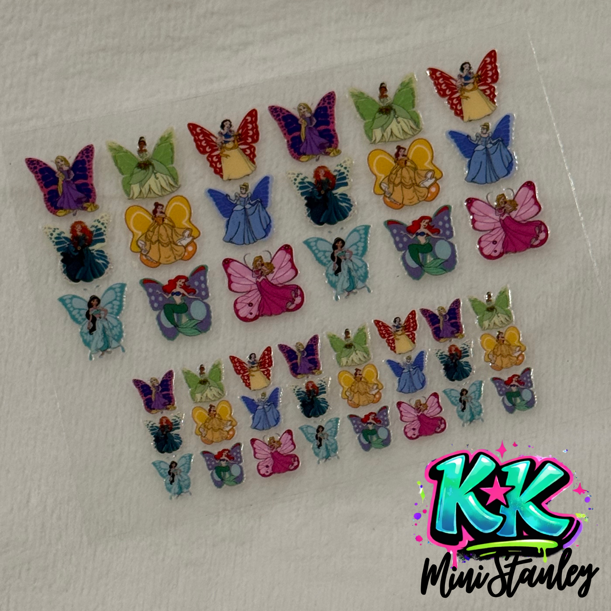 A sheet of UV DTF adhesive decals featuring various Disney princesses with butterfly wings.
