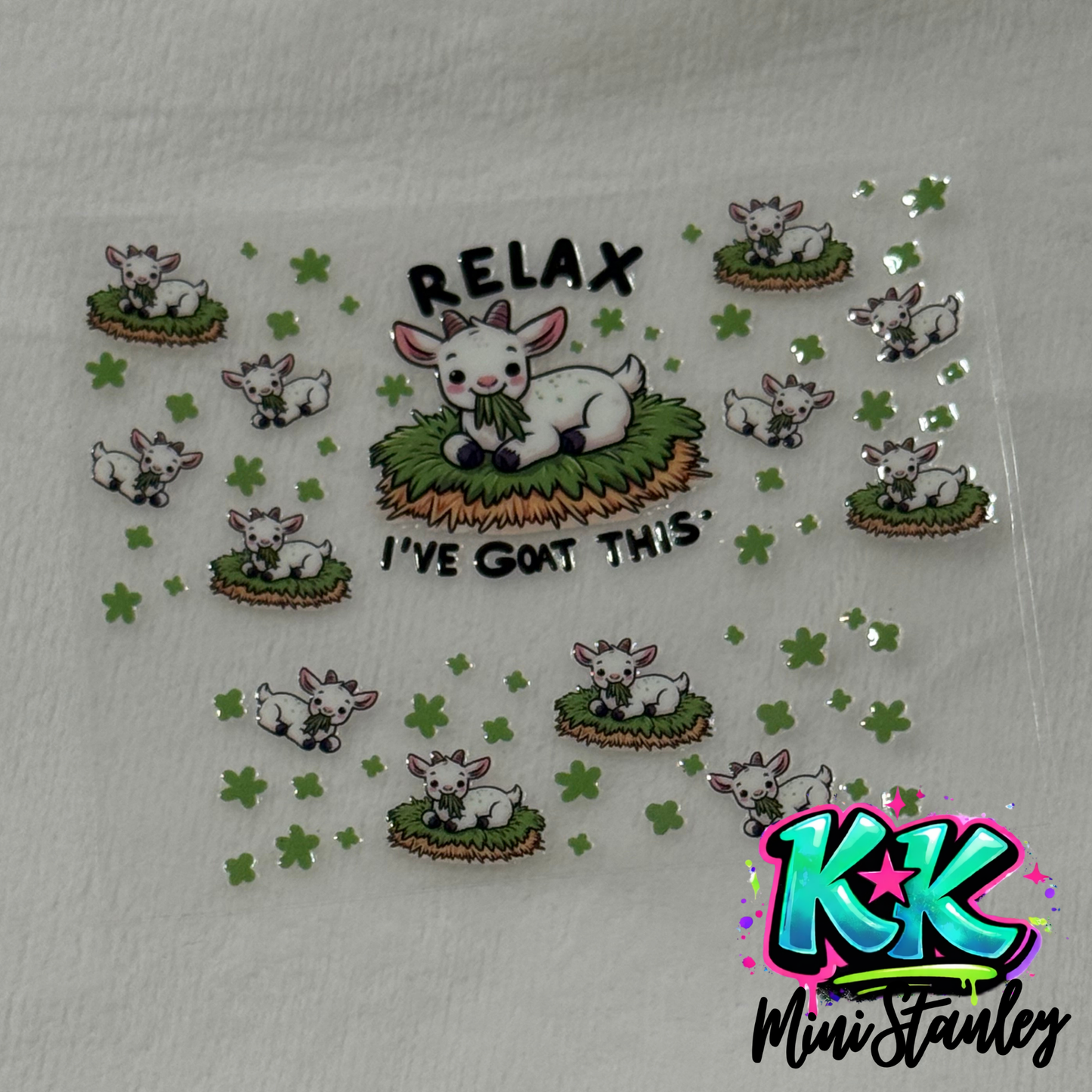 A UV DTF adhesive wrap featuring cartoon goats and clover designs for a mini keychain cup.