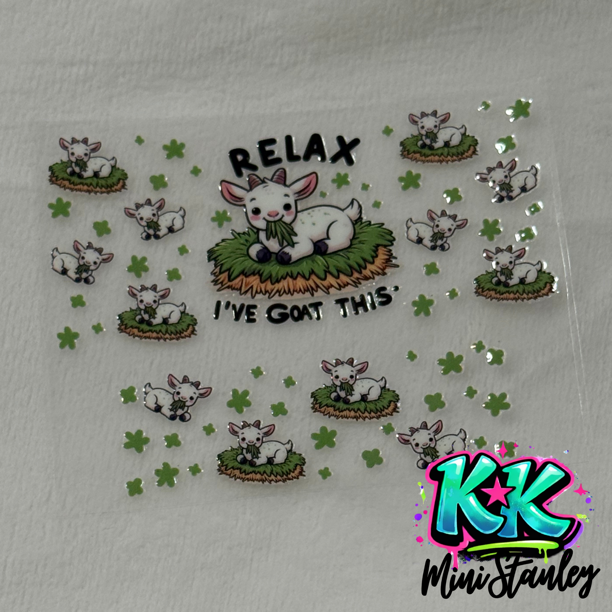 A UV DTF adhesive wrap featuring cartoon goats and clover designs for a mini keychain cup.