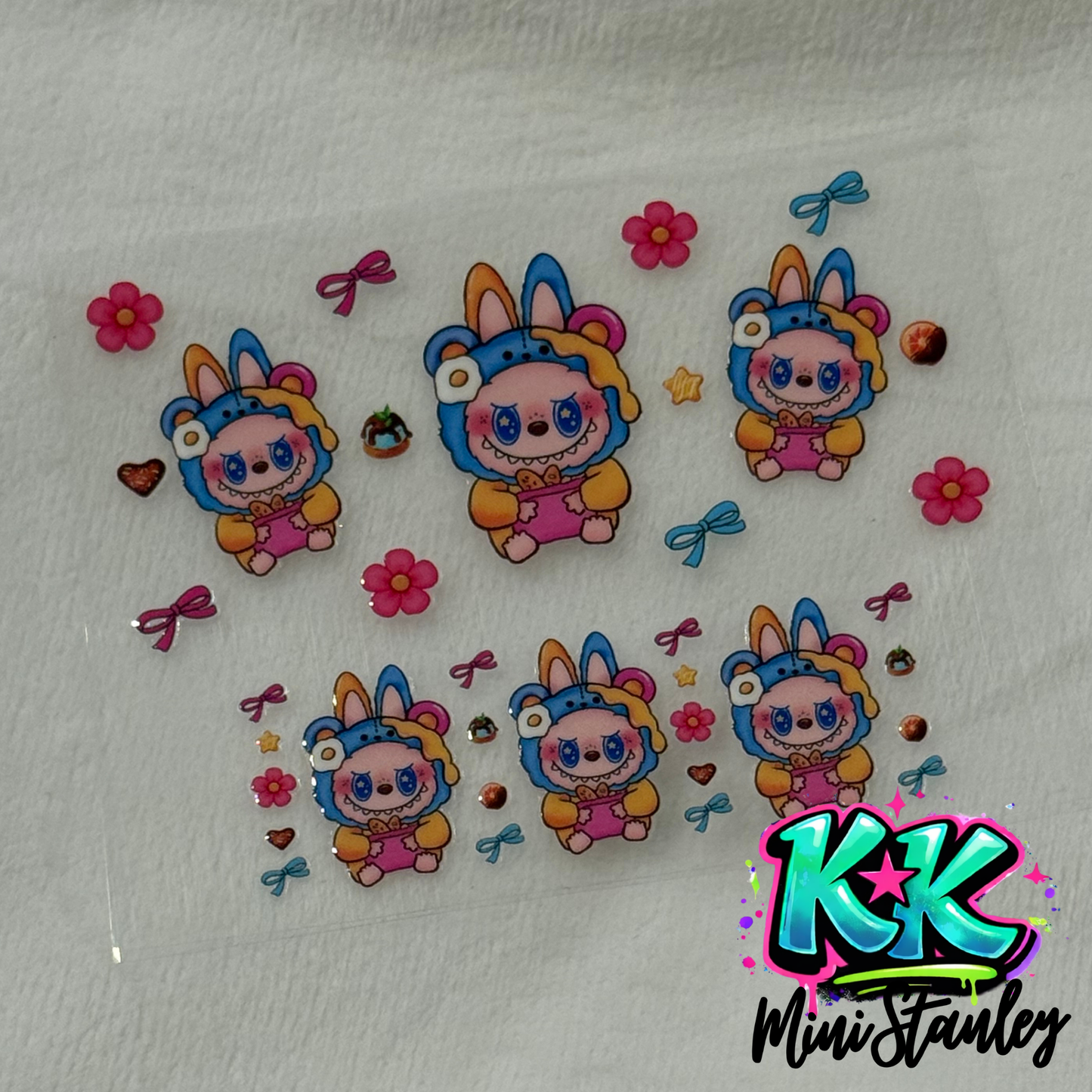 A sheet of UV DTF adhesive decals featuring cartoon bunnies in bear costumes and floral accents.