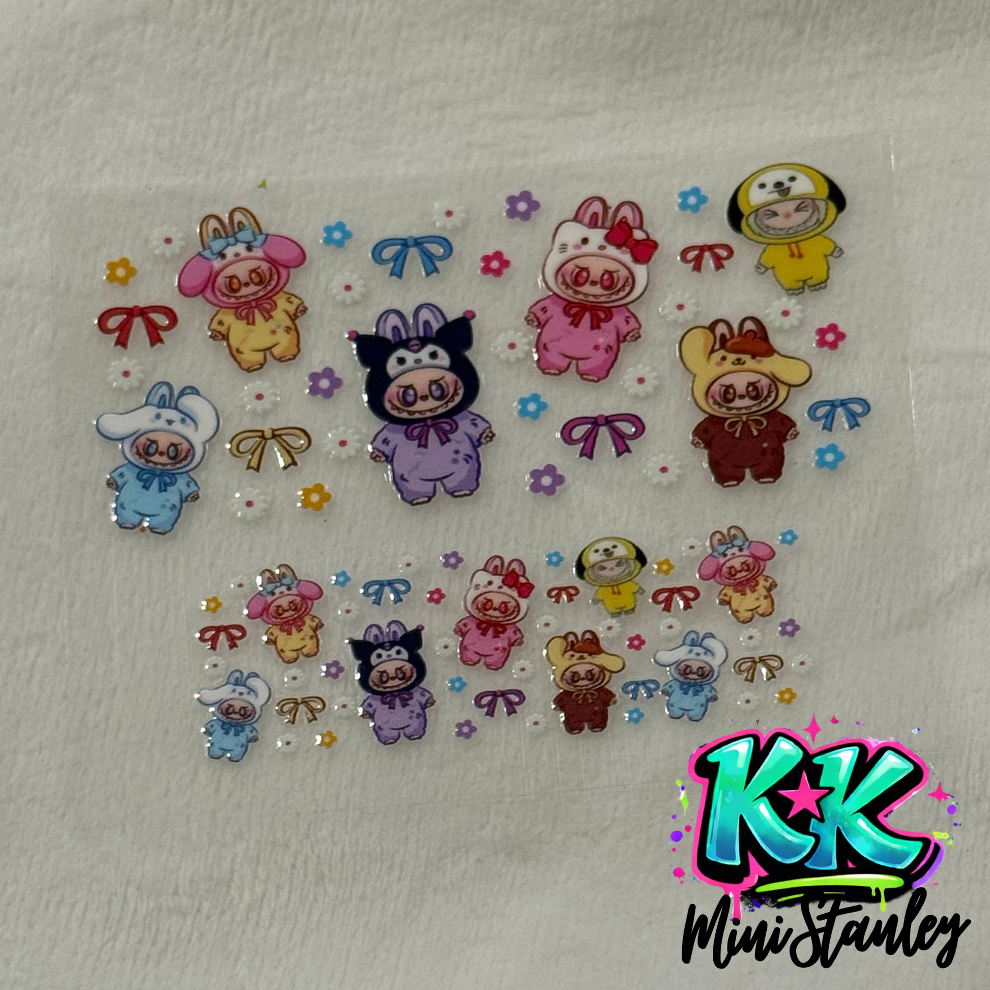 A UV DTF adhesive decal sheet featuring cartoon characters in animal onesies with bows and flowers.