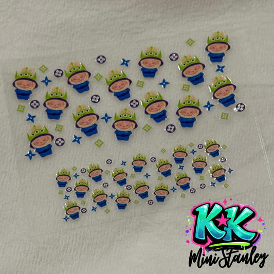 A sheet of UV DTF adhesive transfers featuring cartoon alien characters and floral patterns.