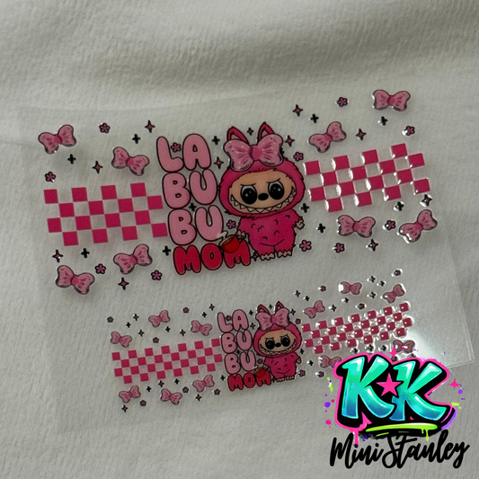 Two pink Labubu character UV DTF cup wraps with checkered patterns and bows on a clear sheet.