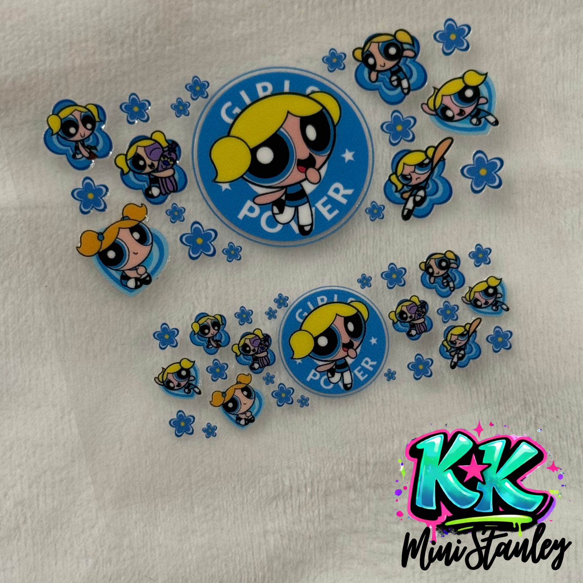 Two sheets of UV DTF adhesive decals featuring Bubbles from The Powerpuff Girls and blue flowers.