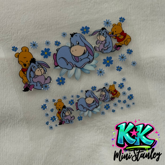 Two UV DTF adhesive wraps featuring Winnie the Pooh and Eeyore surrounded by blue flowers.