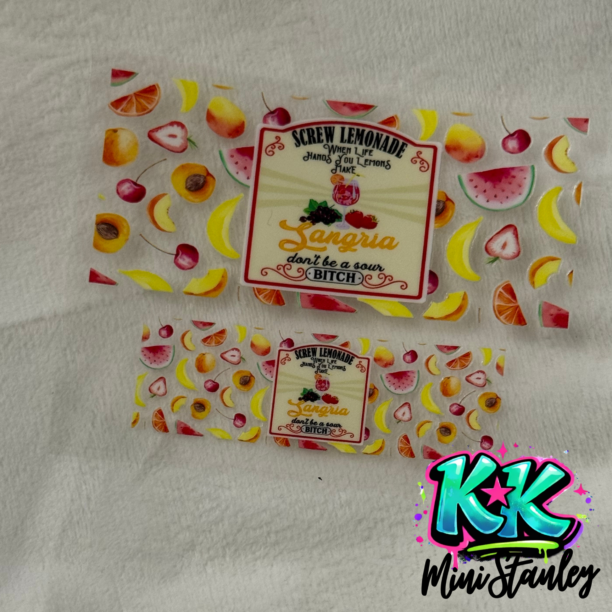 Two UV DTF adhesive wraps featuring a fruit pattern and a sangria-themed label design.