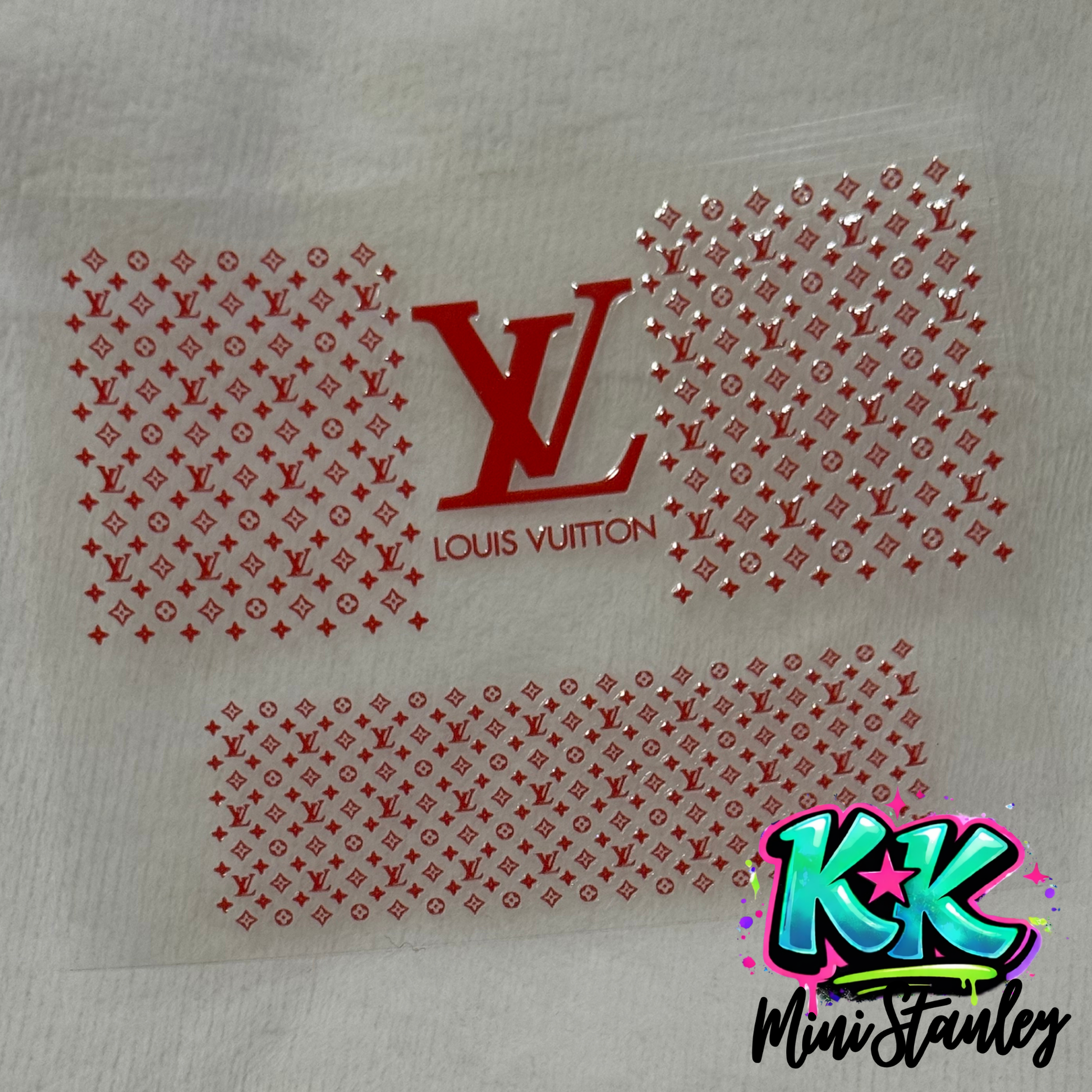 A red Louis Vuitton logo and monogram pattern UV DTF adhesive wrap for mini keychains.