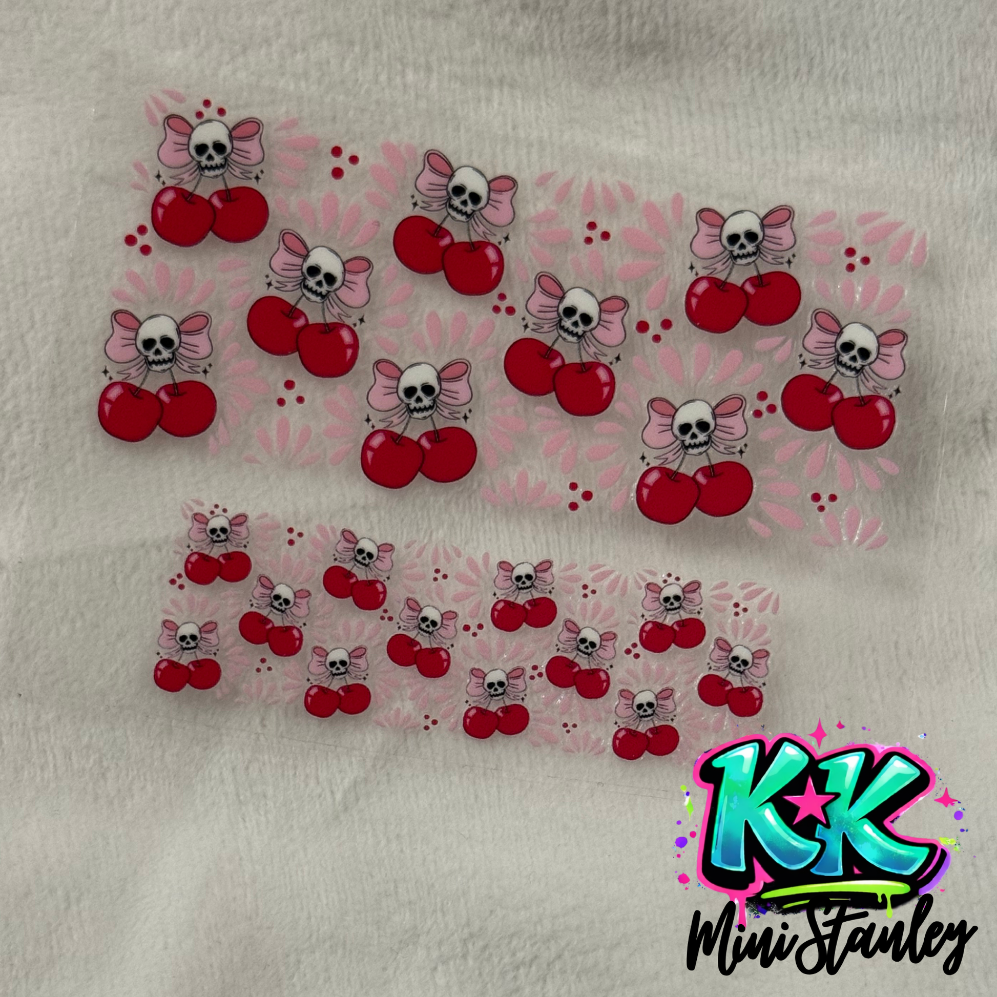 Two sheets of UV DTF decals featuring a pattern of pink bows, skulls, and red cherries.