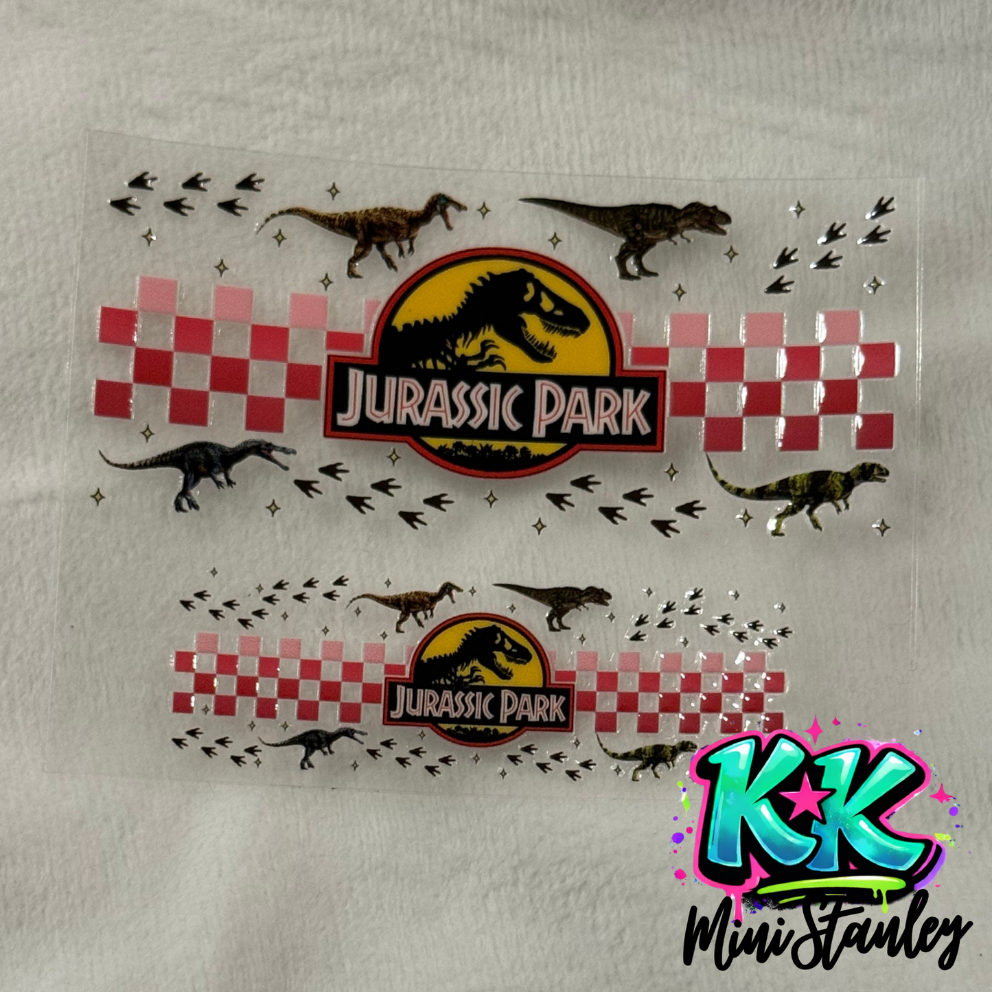 Two Jurassic Park themed UV DTF adhesive wraps for mini cups featuring dinosaurs and checkers.