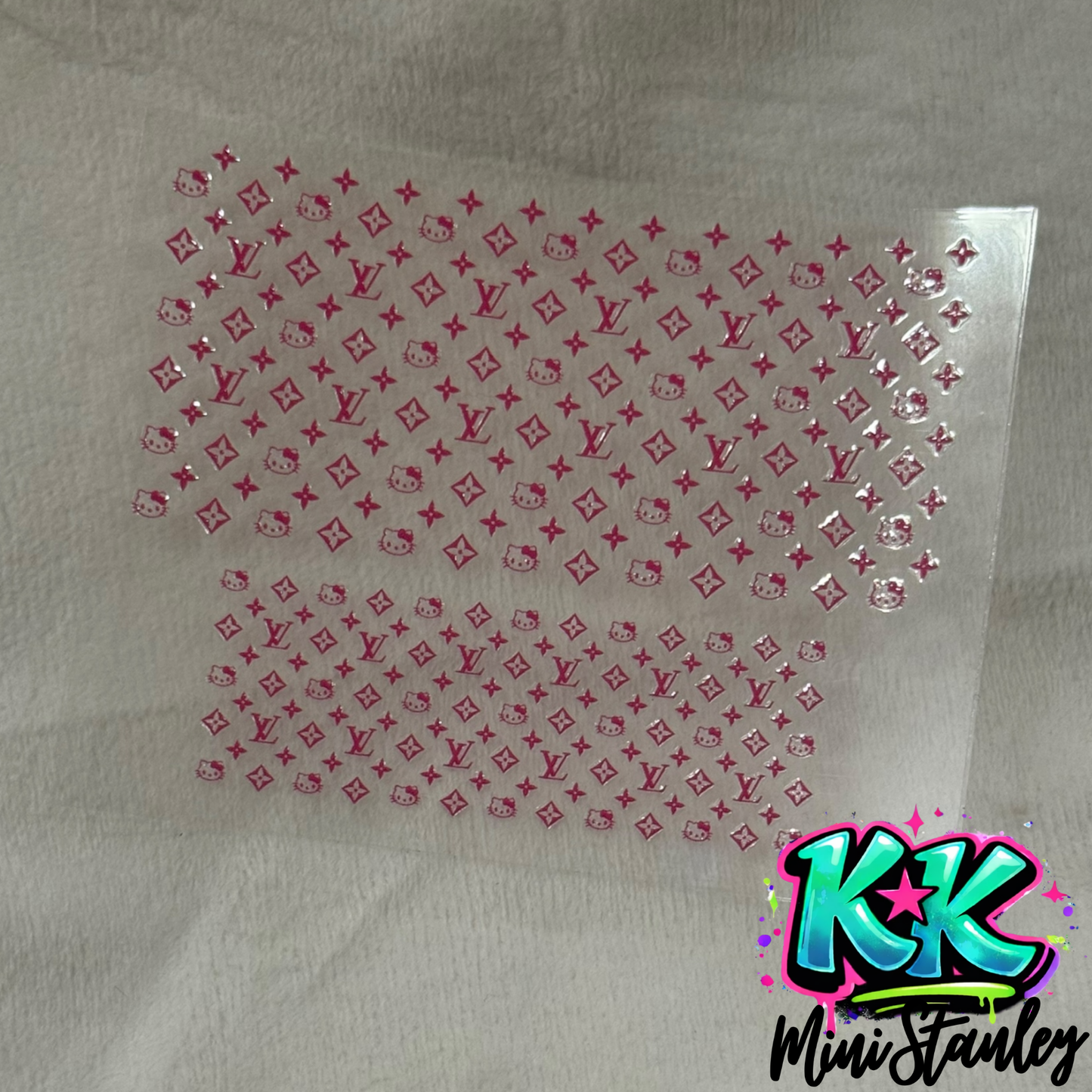A pink UV DTF adhesive wrap featuring a repeating pattern of Hello Kitty and floral logos.