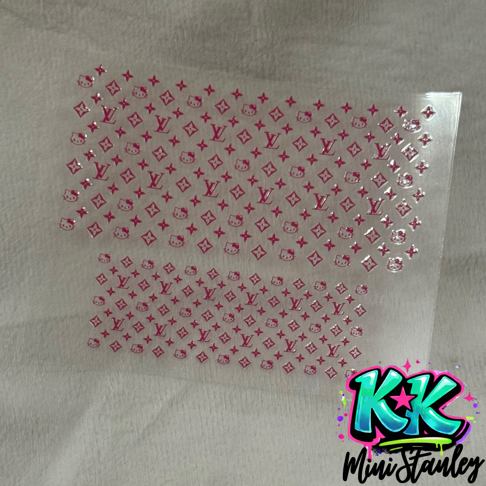A pink UV DTF adhesive wrap featuring a repeating pattern of Hello Kitty and floral logos.