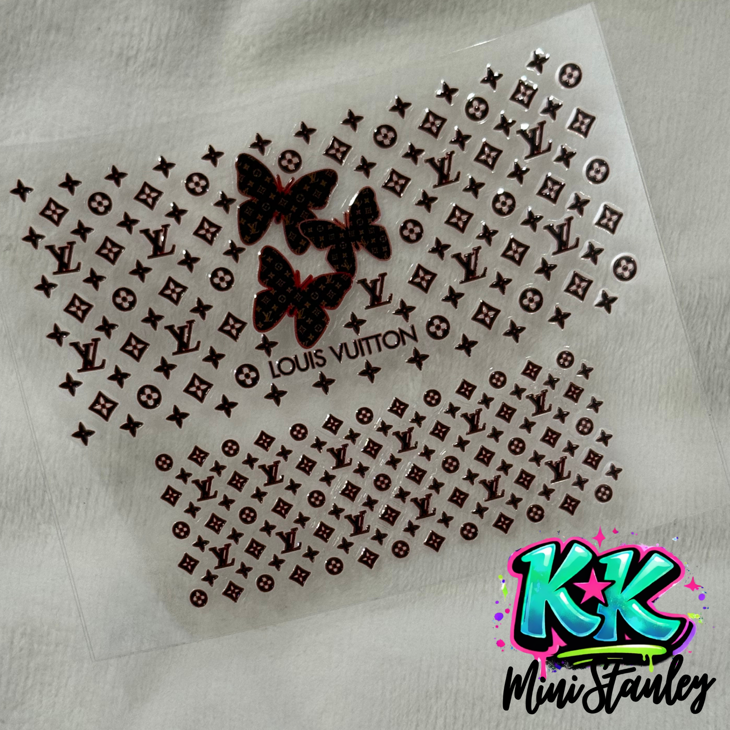 A sheet of UV DTF adhesive decals featuring brown Louis Vuitton logos and butterfly designs.