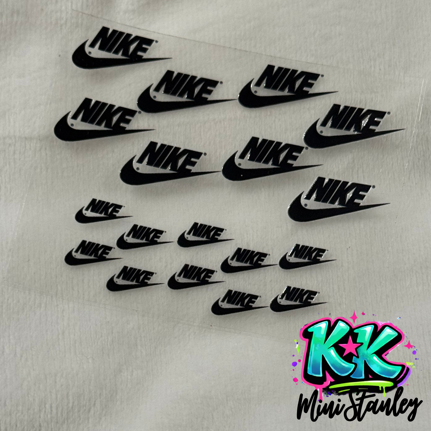 A sheet of black Nike logo UV DTF adhesive decals for mini keychains.