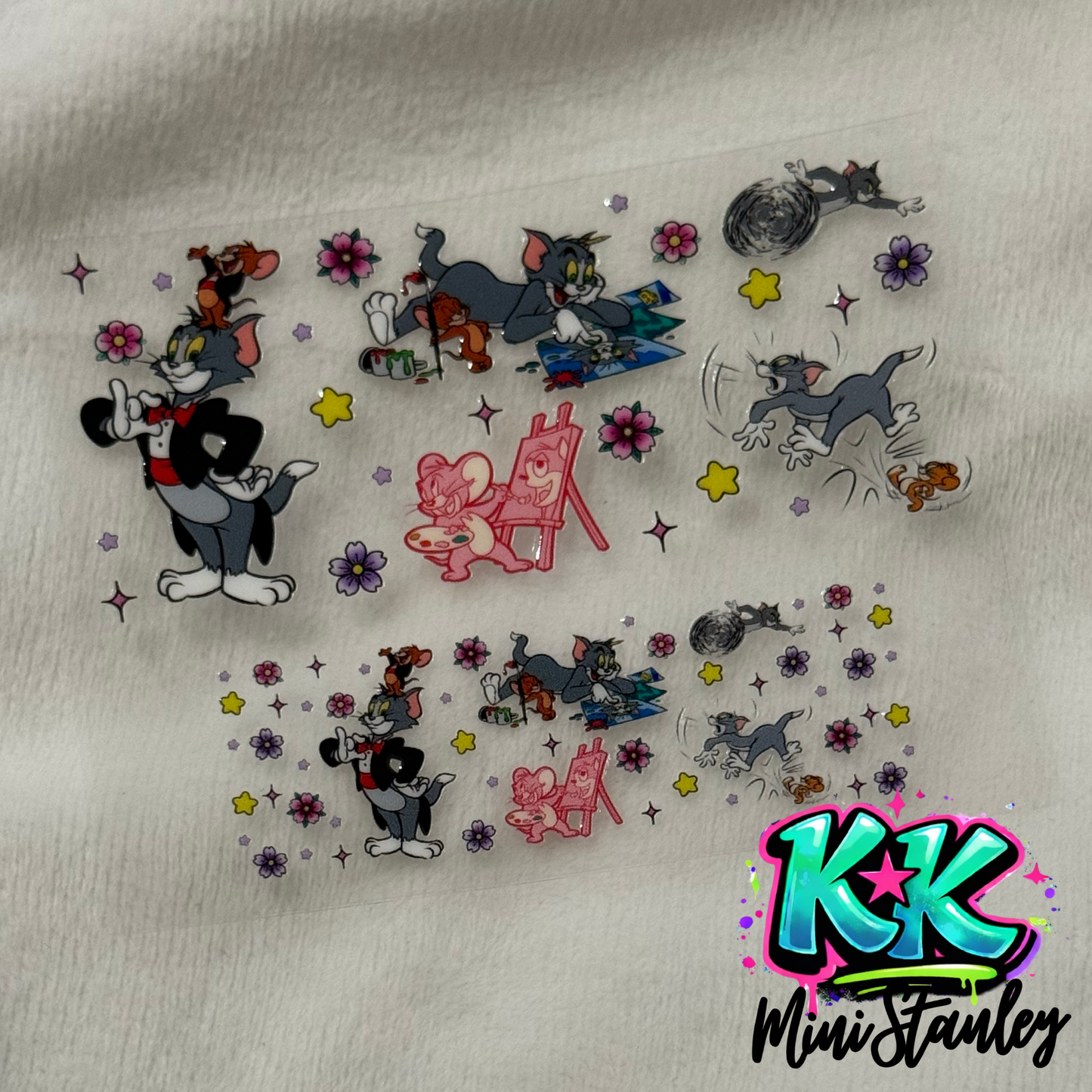 Two sheets of Tom and Jerry themed UV DTF adhesive transfers featuring floral accents.