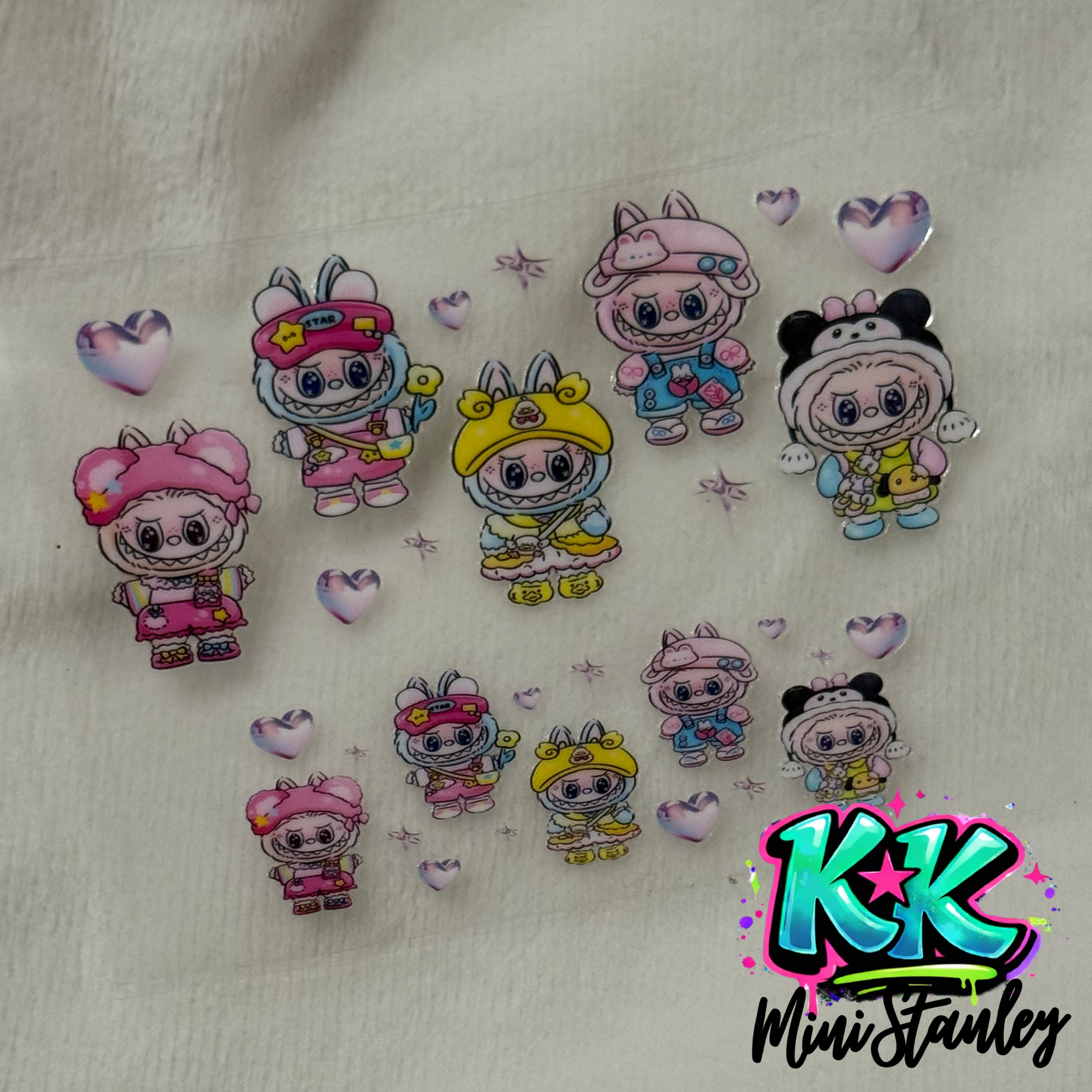 A sheet of UV DTF adhesive decals featuring cartoon characters in animal hats and small hearts.