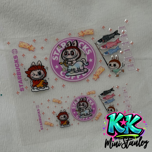 Two UV DTF adhesive cup wraps featuring cartoon characters and Starbucks-themed designs.