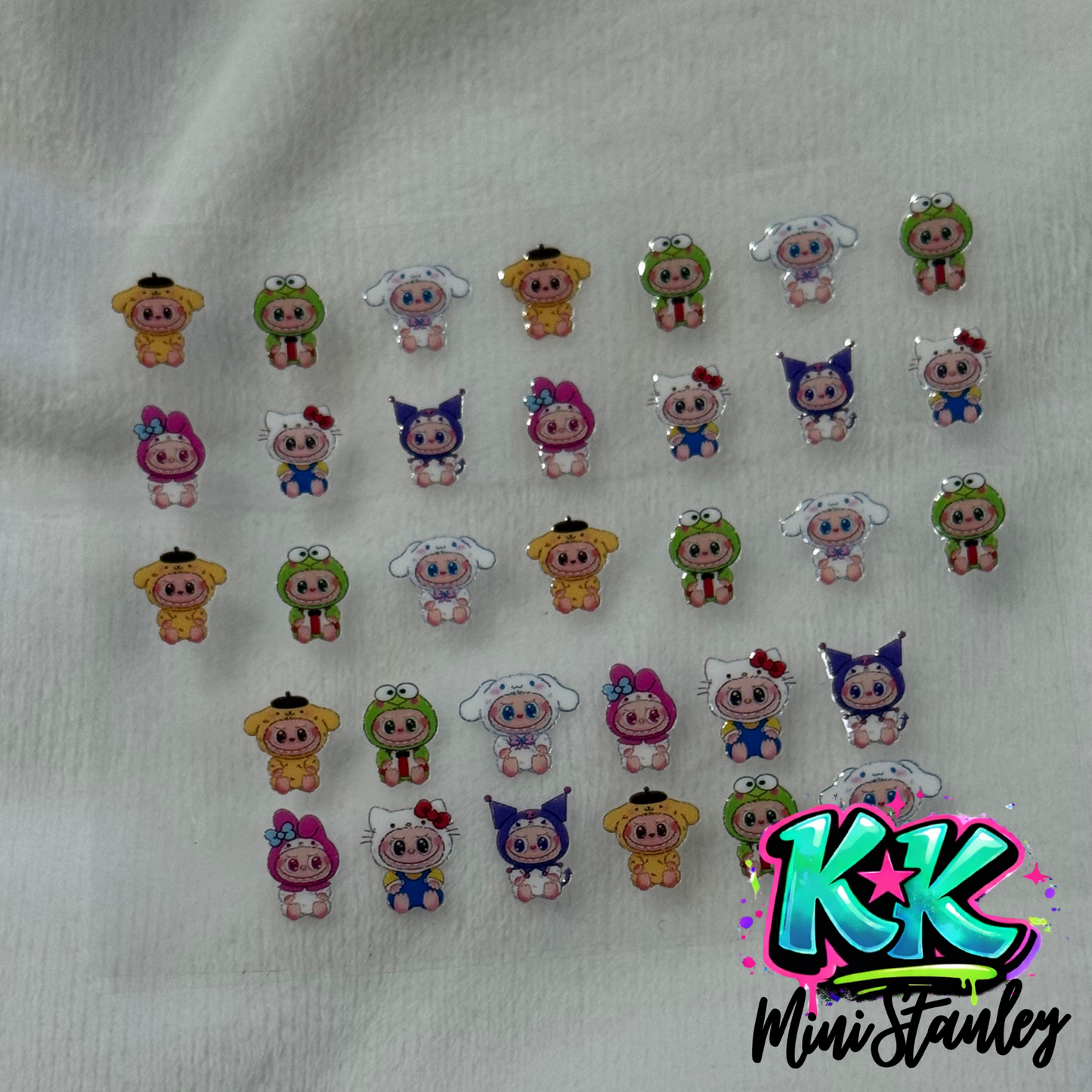 A sheet of UV DTF adhesive decals featuring various Sanrio characters in baby costumes.