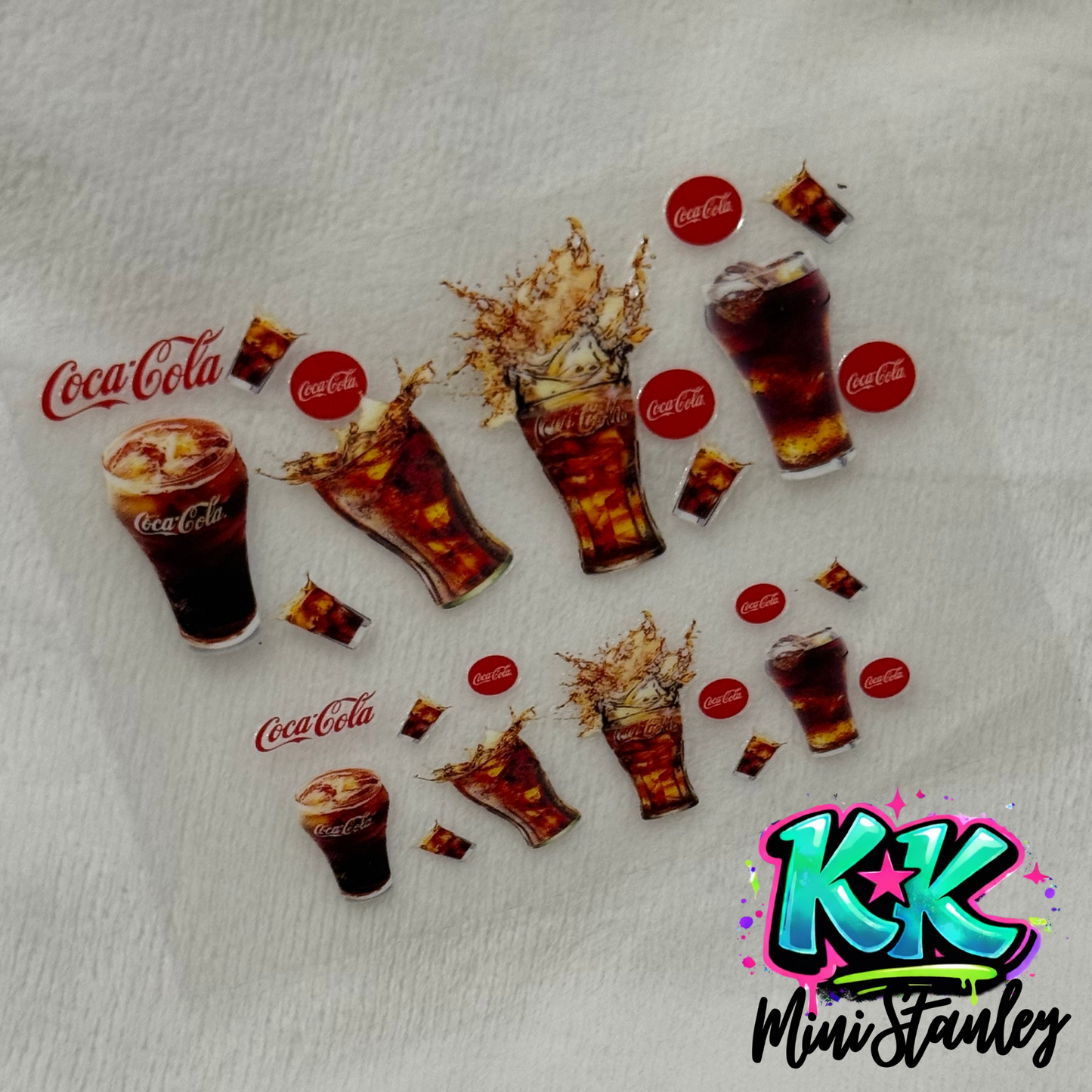 A UV DTF adhesive decal sheet featuring Coca-Cola themed glass cup designs and logos.