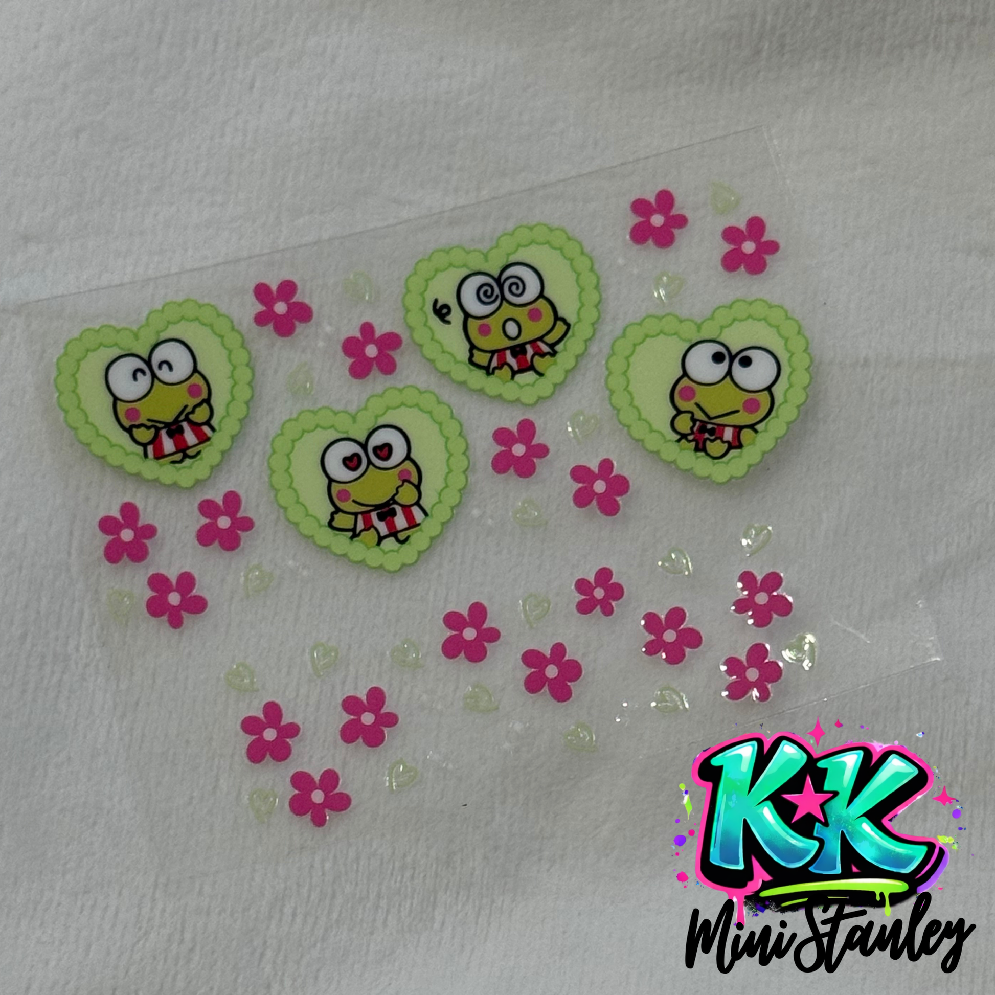 A UV DTF decal sheet featuring Keroppi characters in green hearts and small pink flowers.