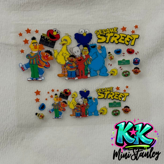Two UV DTF adhesive decals featuring KAWS Sesame Street characters on a clear backing.