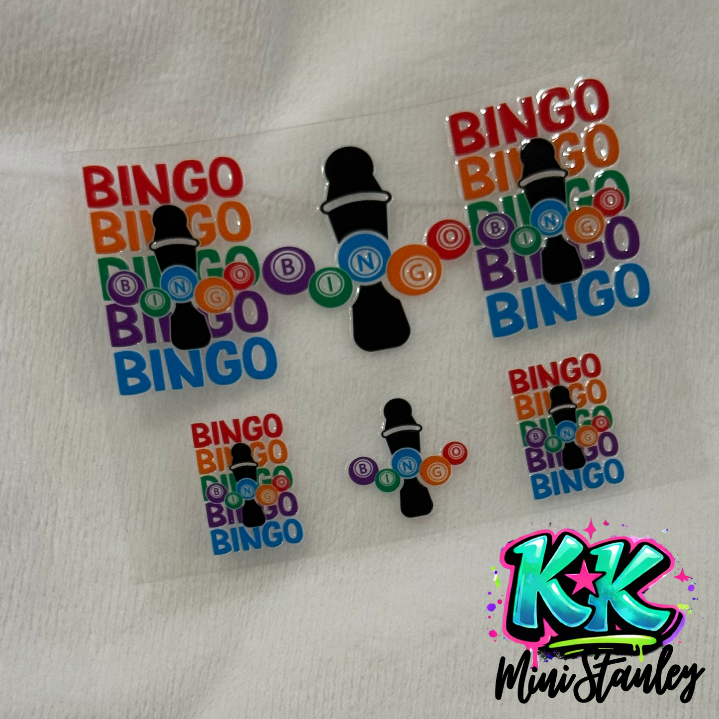 A sheet of UV DTF adhesive decals featuring bingo-themed designs with daubers and colorful balls.