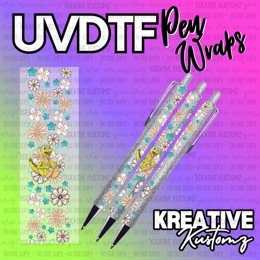 A floral UV DTF pen wrap decal featuring a cartoon dinosaur and teal stars on a glittery pen.