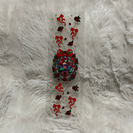 A clear UV DTF pen wrap featuring Ariel surrounded by red roses, bows, and gold stars.