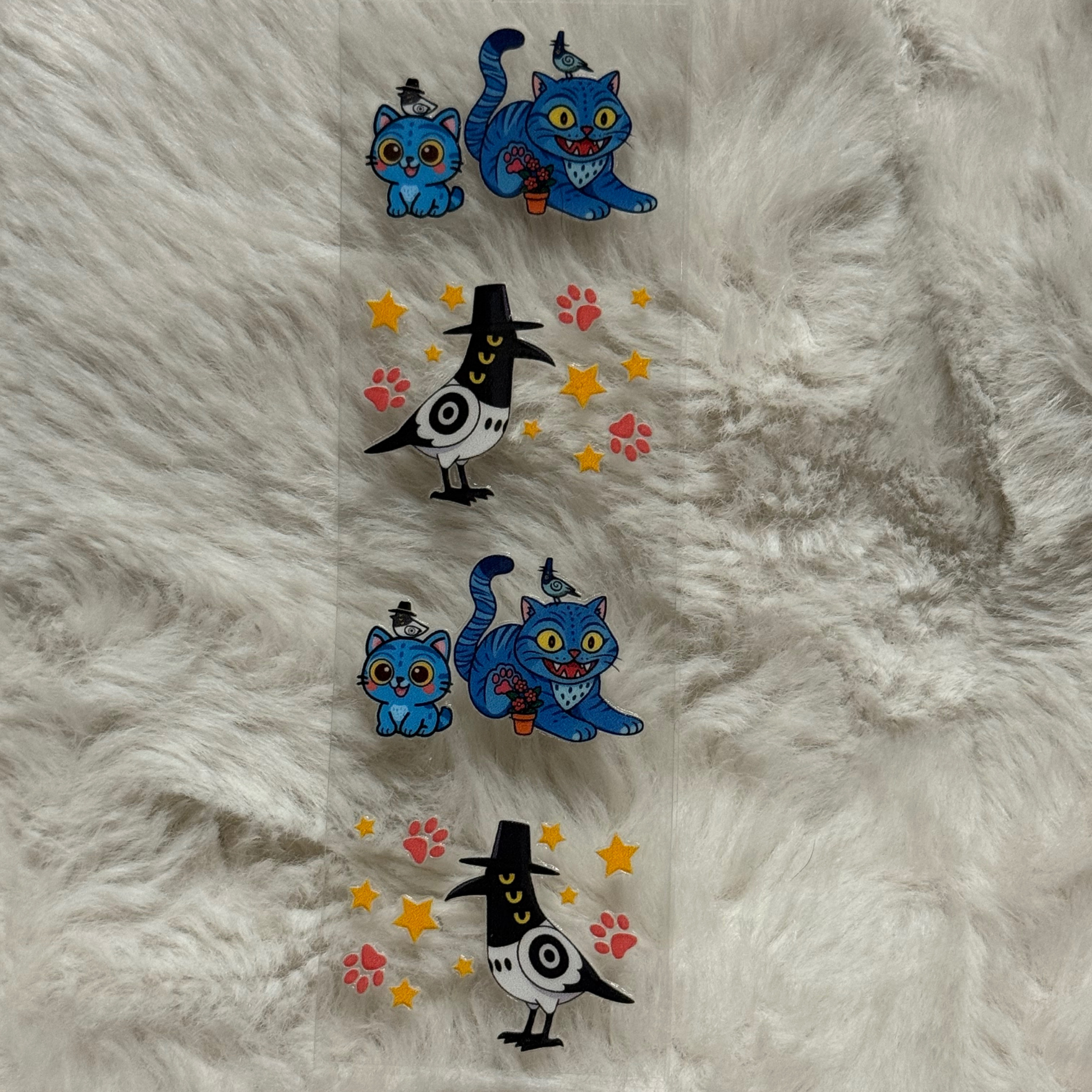 A clear adhesive pen wrap featuring repeating patterns of blue cats and birds in top hats.