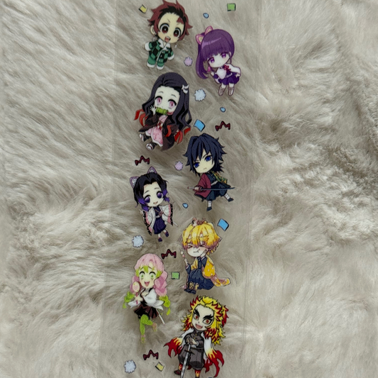 A clear adhesive pen wrap featuring chibi characters from Demon Slayer on a fuzzy background.